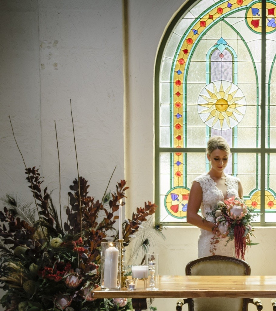 Bride in front of stain glass window of wedding chapel.